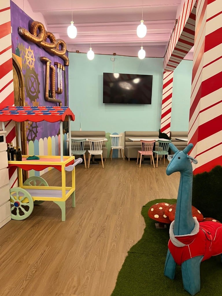 Interior de Charlie con columnas de caramelo, carrito de juguete y jirafa de peluche
