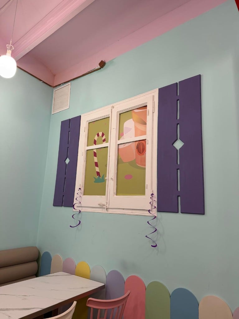 Ventana decorativa con contraventanas lilas y mural de caramelos en el interior de Charlie