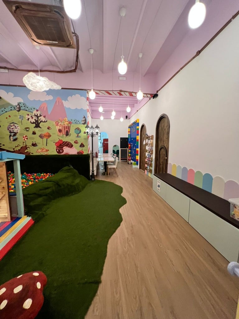 Pasillo de la zona de juegos de Charlie, con césped, piscina de bolas y banco corrido