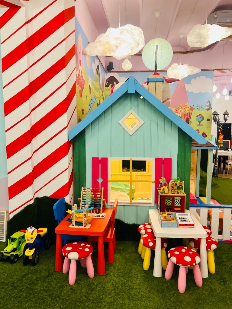 Rincón de juegos de Charlie Restaurante, con casita, taburetes de seta y juguetes